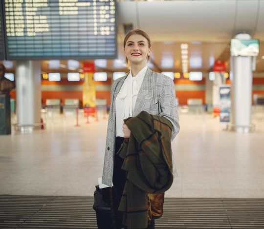 a woman standing in an airport with her baggage